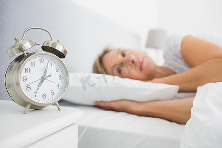 金发女人躺在床上，闹钟显示时间还早