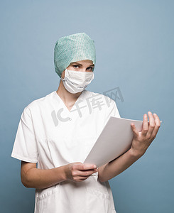 戴口罩的科学家摄影照片_戴外科口罩的护士和一本面向镜头的杂志