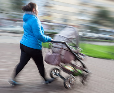 婴儿在行动摄影照片_有小孩的母亲和一辆婴儿车走在街上
