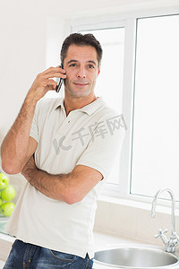 手机版电商首页摄影照片_英俊的男人在厨房里使用手机