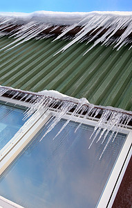 雪屋顶摄影照片_许多冰柱挂在小木屋的屋顶上