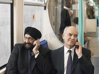 坐在通勤火车上使用手机的多民族商人