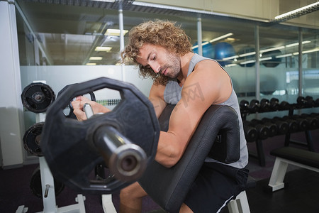 肌肉男在健身房举杠铃的侧视图