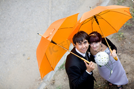 拿着橙色雨伞的新娘和新郎的肖像