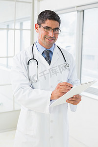 微笑的男医生在医院写报告