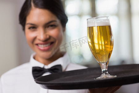 漂亮的女服务员拿着托盘和一杯啤酒