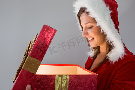 打开礼物的俏丽的圣诞老人女孩