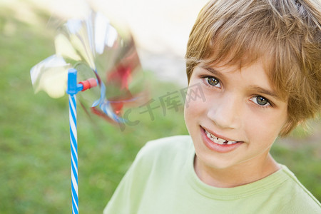 在公园里拿着风车的微笑男孩的特写