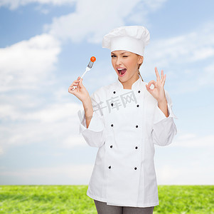 素食标志摄影照片_拿着叉子和西红柿的微笑女厨师