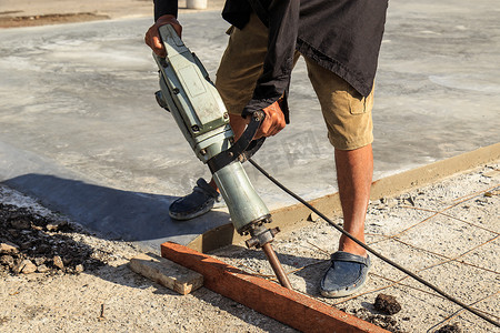 工程地摄影照片_工人在地面上使用建筑钻孔水泥