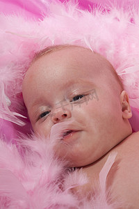 婴儿毛毯摄影照片_三个月大的婴儿躺在粉红色的毛毯上，身上挂着粉红色的蟒蛇