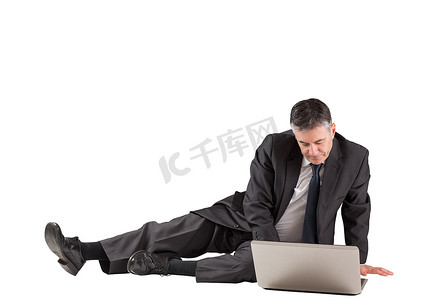 专注于躺在地板上使用笔记本电脑的商人