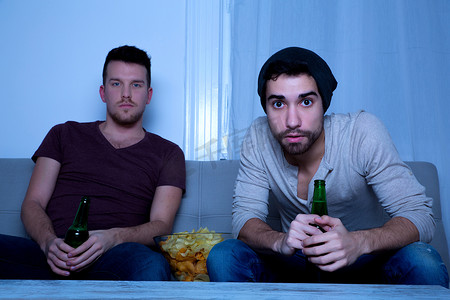 啤酒电商首页摄影照片_两个朋友用啤酒和薯条热情地看电视