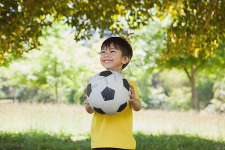 在公园踢足球的快乐可爱小男孩