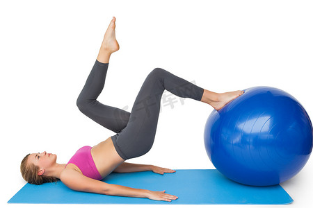 一个健康的女人用健身球锻炼的侧视图