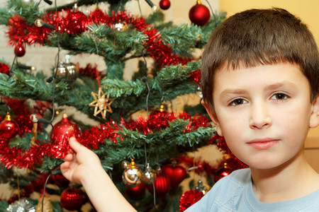 圣诞球红色摄影照片_拿着圣诞装饰品的小男孩