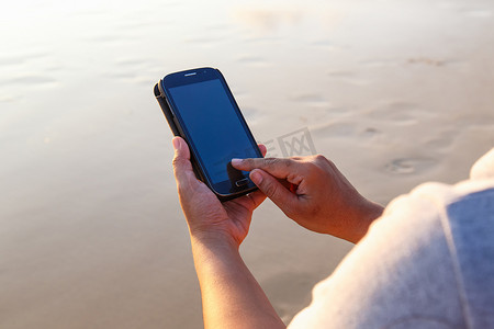泰国女人在海滩上使用智能手机