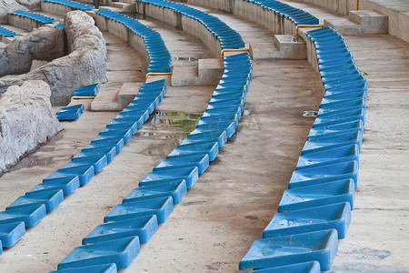 蓝色座椅摄影照片_体育场上的旧塑料蓝色座椅