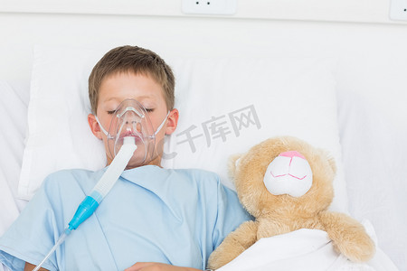 戴着氧气面罩睡在毛绒玩具旁边的男孩
