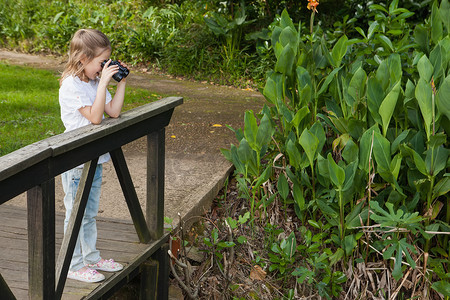一个女孩在公园用双筒望远镜看的侧视图