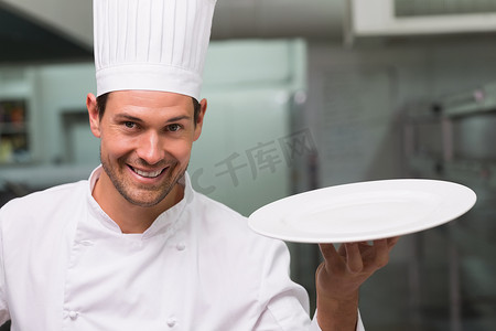 拿着盘子对着镜头微笑的厨师