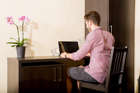 在亚洲风格的酒店房间里使用笔记本电脑的年轻人