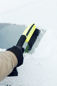 男人用刷子清理汽车挡风玻璃上的雪