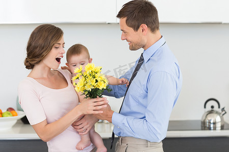 父亲给抱着孩子的母亲一束黄色的花