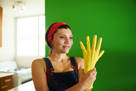 年轻的西班牙裔妇女戴着黄色乳胶手套打扫家务