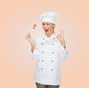 素食标志摄影照片_拿着叉子和西红柿的微笑女厨师