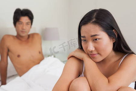 男朋友看着坐在床尾的女朋友