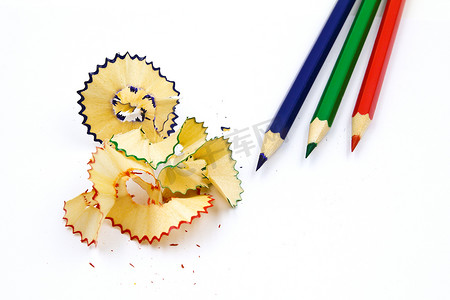 彩色铅笔创意艺术摄影照片_彩色铅笔，白色背景上有彩色铅笔屑