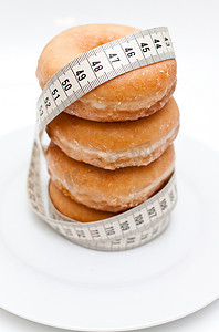 体重增加摄影照片_一组被卷尺包围的甜甜圈