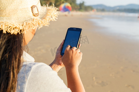 泰国女人在海滩上使用智能手机