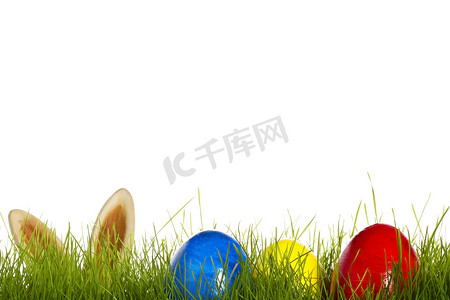 草地上的三个复活节彩蛋，背景是一只复活节兔子的耳朵