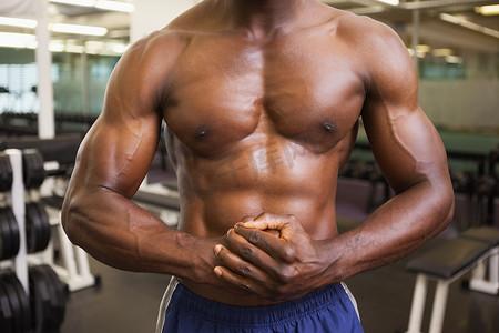 一个光着膀子的肌肉男在健身房的中段