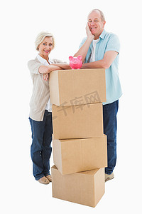 老箱子摄影照片_老夫妇拿着移动的箱子和存钱罐对着镜头微笑