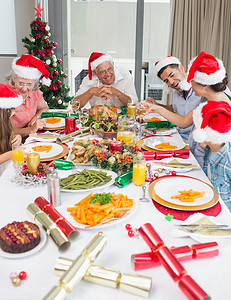 戴着圣诞帽的幸福家庭享受圣诞晚餐