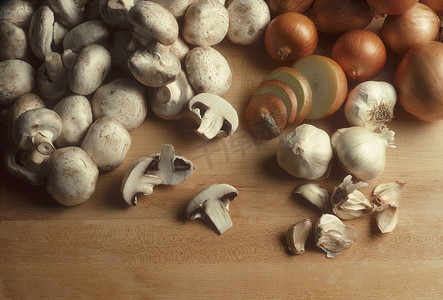洋葱和大蒜摄影照片_肉块表面上的蘑菇、洋葱和大蒜