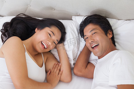 幸福的夫妻躺在床上对着镜头微笑