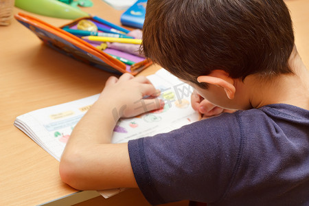 男孩用彩色铅笔做作业，画水果