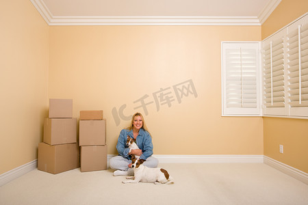 移动首页摄影照片_漂亮的女人和狗在地板上的房间里移动箱子