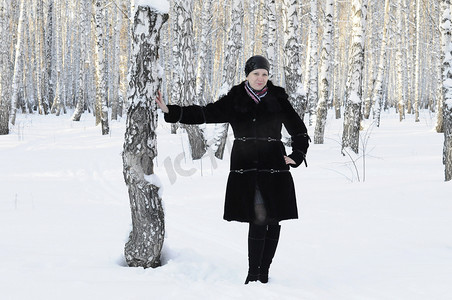 皮毛女人摄影照片_穿黑色裘皮大衣的女人在白桦林中取胜