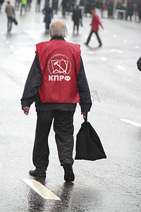 俄罗斯胜利日摄影照片_在共产主义者游行的日子里，孤独的老人手里拿着一个袋子领取养老金