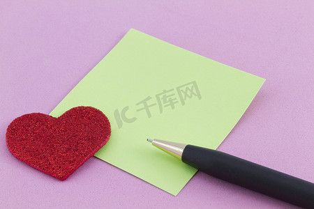 粉红色背景中的红心、绿色笔记和笔