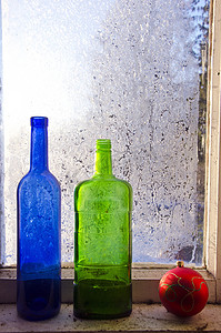 新年圣诞玩具和两个旧瓶子在冬天的窗户上结霜