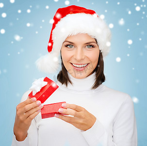红色小雪花摄影照片_戴着圣诞帽、带小礼盒的微笑女人