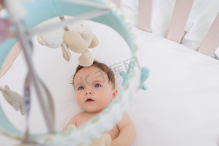 婴儿看着挂在婴儿床上的玩具