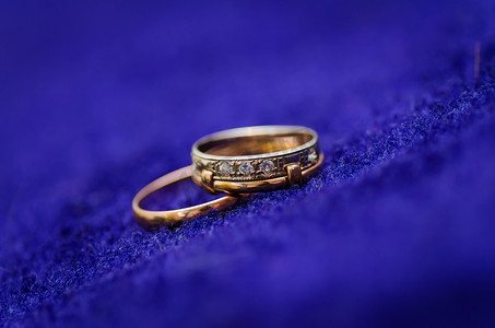 蓝色背景上的两个金色闪亮结婚戒指。