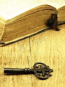 钥匙和旧的，打开的书，封面有损坏。
